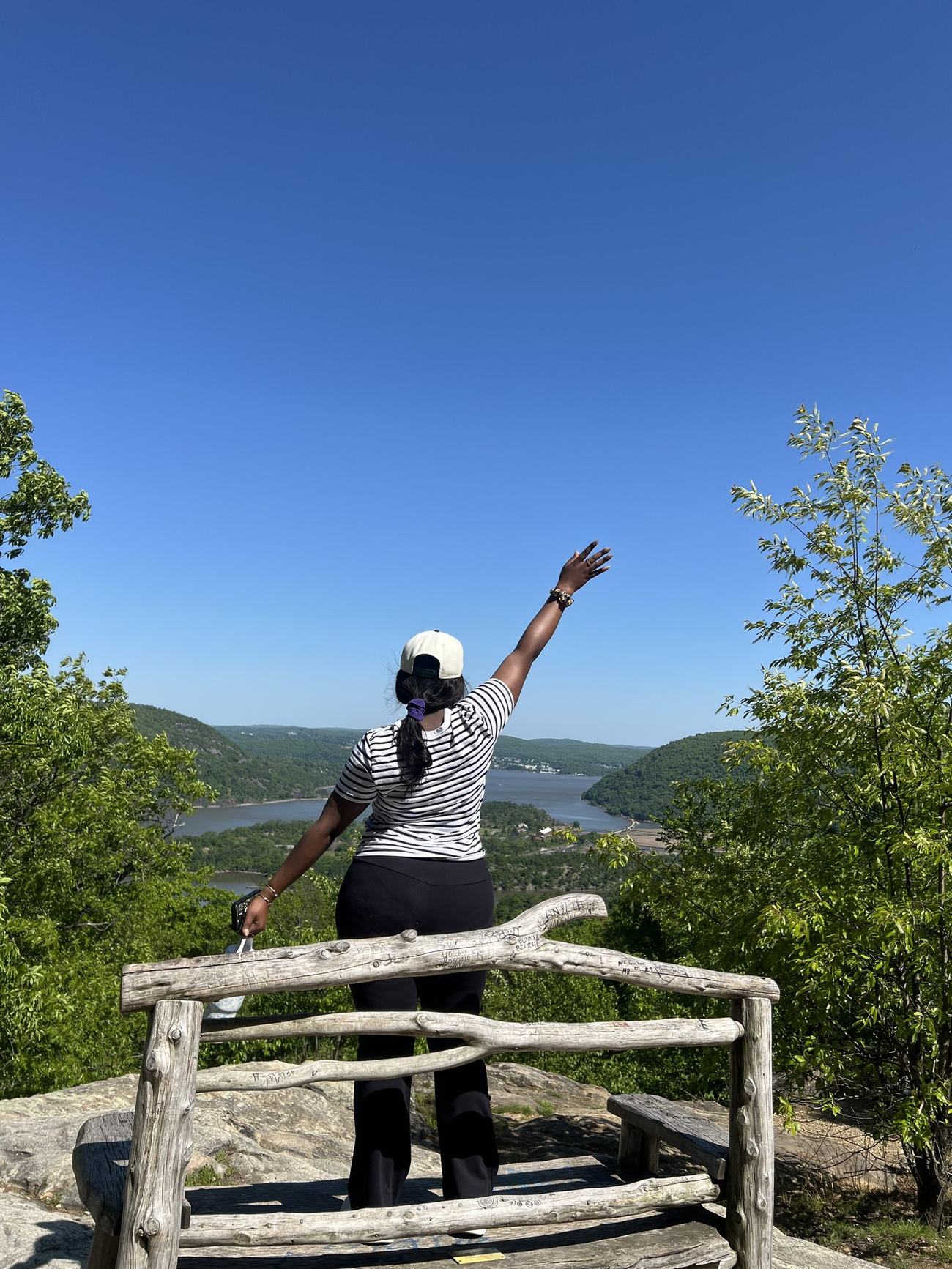 A MAGIS hiker raising her hand toward the sky at a scenic overlook